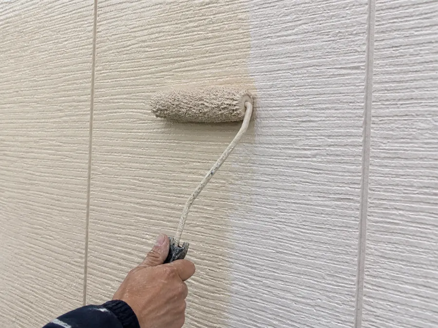 住宅の外壁をローラーで塗装しているところ